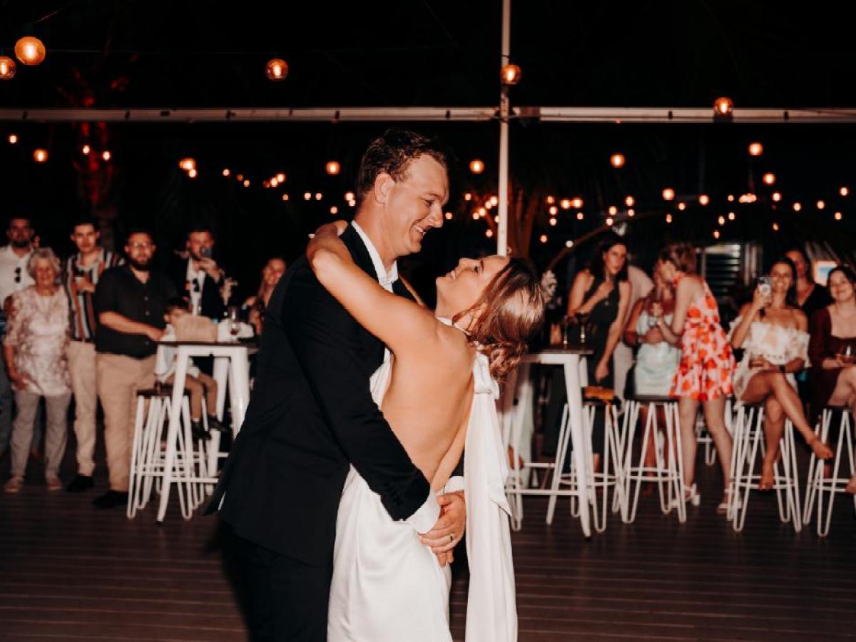 Couple dancing at a wedding reception with guests watching.