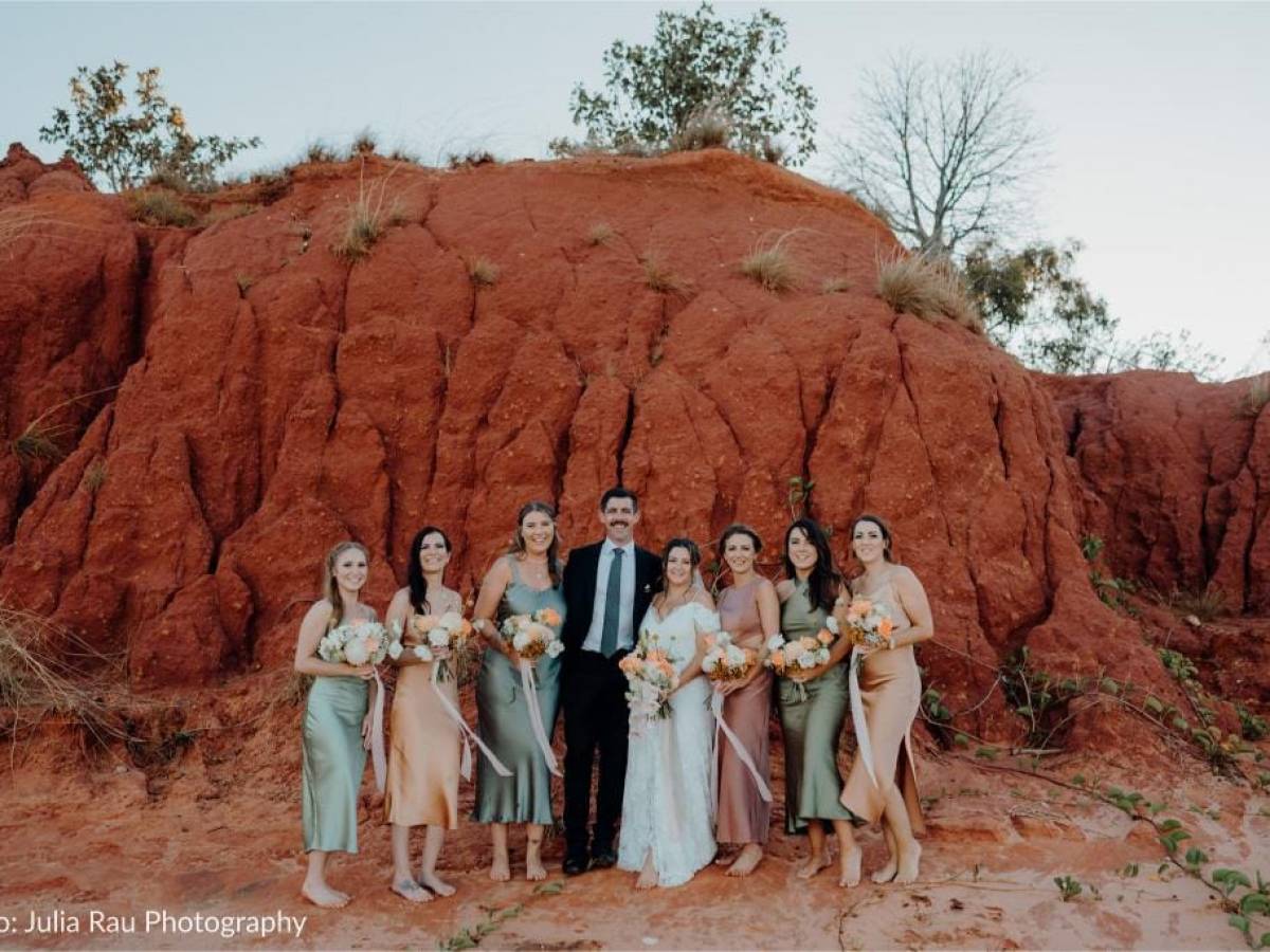 Group of people in formal wear pose against a red rock backdrop.