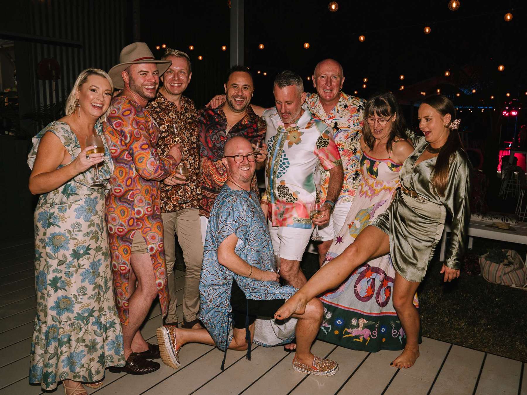 A group of people in colorful outfits posing together at an outdoor event.