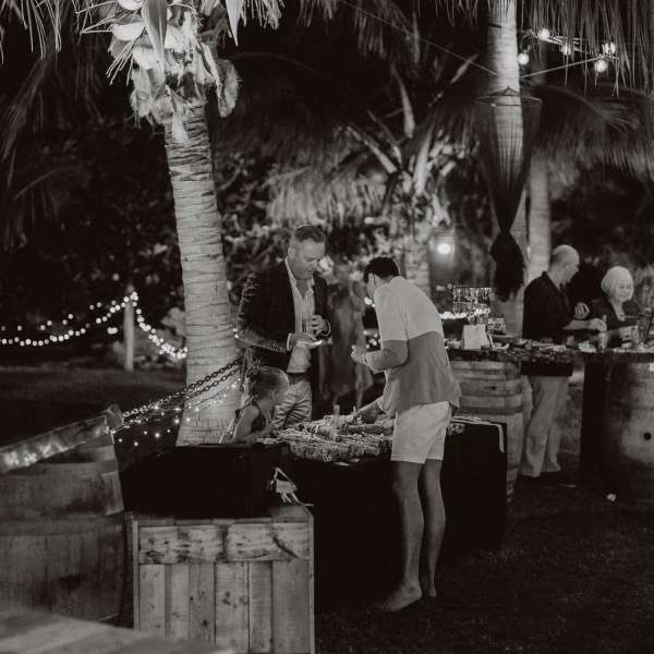 Black and white photo of people at an outdoor night event with string lights.