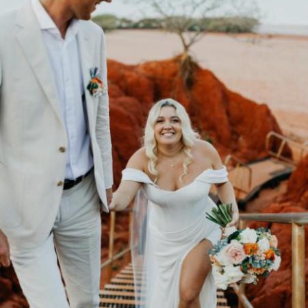 Bride and groom walking up steps with red rock background.