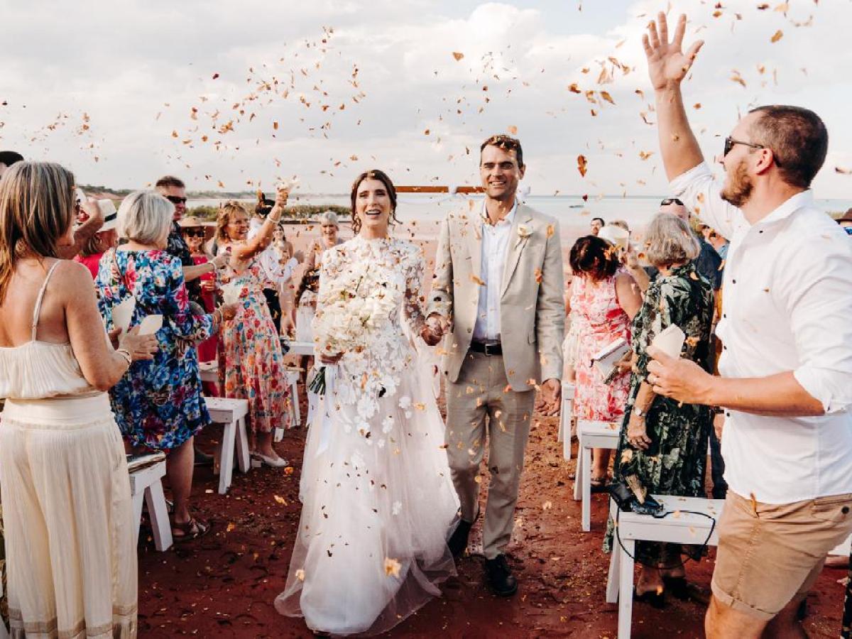 Bride and groom walk through a crowd throwing flower petals in celebration.