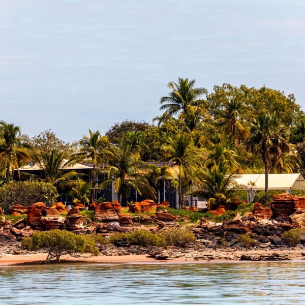Tropical beach with palm trees and rocky shoreline.