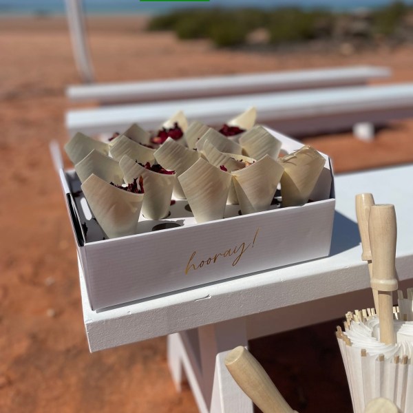 Tray with cones and umbrellas on a white table, sandy background.