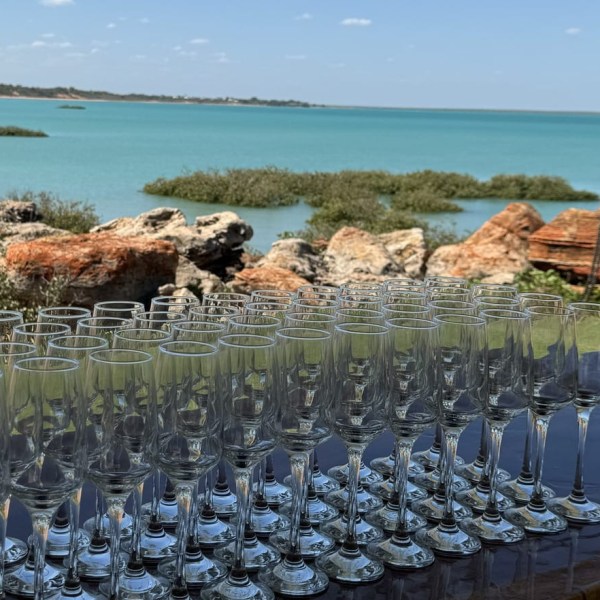 Empty glasses on a table with a scenic ocean view and rocky shoreline.